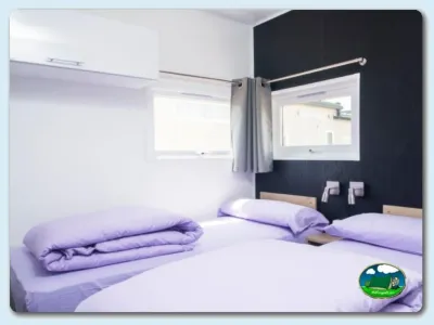 Bungalow interior con dos camas y espejo del Camping Las Dunas, Sant Pere Pescador (Girona)