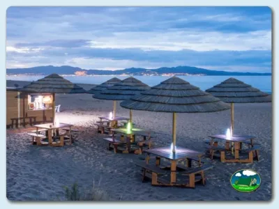 Playa con bungalow y sombrillas al atardecer junto al mar del Camping Las Dunas, Sant Pere Pescador (Girona)