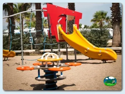 Parque infantil con tobogán amarillo y columpios del Camping Las Dunas, Sant Pere Pescador (Girona)