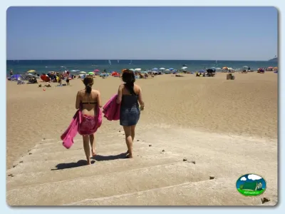 Playa junto al mar con bañistas y sombrillas del Camping Las Dunas, Sant Pere Pescador (Girona)