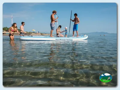 Playa junto al mar, familia en tabla de paddle surf del Camping Las Dunas, Sant Pere Pescador (Girona)