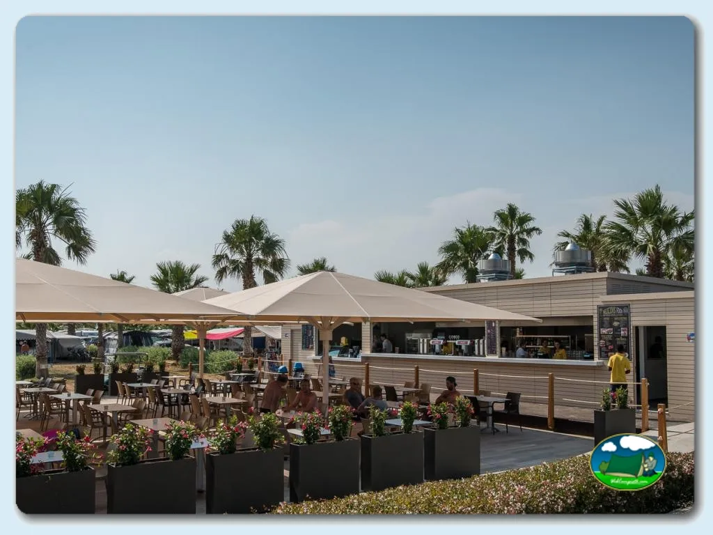 Restaurante con terraza y vistas a palmeras del Camping Las Dunas, Sant Pere Pescador (Girona)