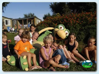Parque infantil con niños y mascota verde del Camping Las Dunas, Sant Pere Pescador (Girona)