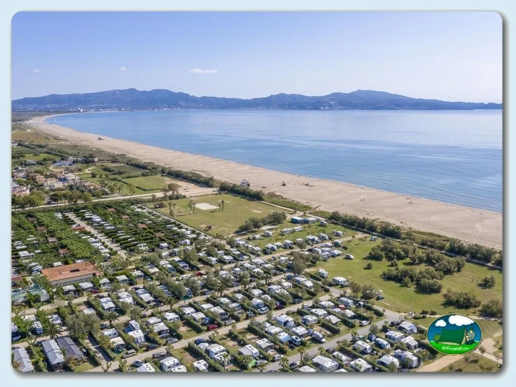 Playa junto al mar con vistas a la montaña, parcelas y mobil-homes del Camping L'Amfora, Sant Pere Pescador (Girona)