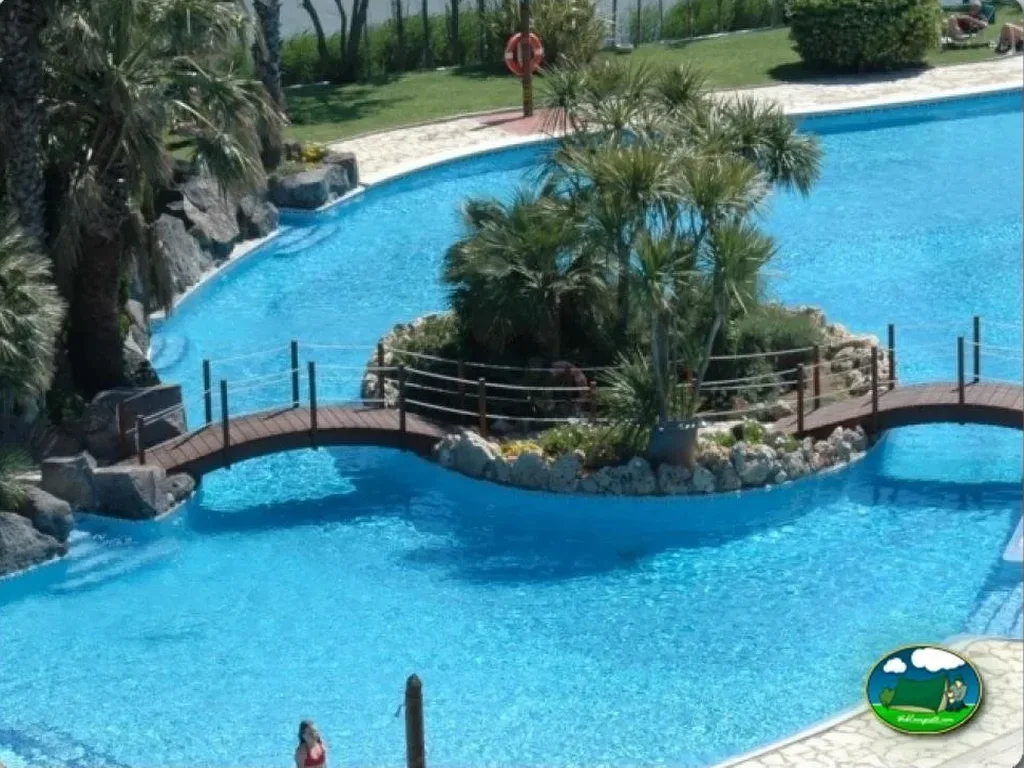 Piscina con puente decorativo y vistas al jardín del Camping Nautic Almata, Castelló d'Empúries (Girona)
