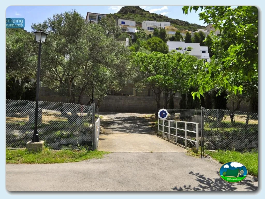 Entrada del recinto con puerta y parcelas arboladas del Camping Ampurdanés, Roses (Girona)
