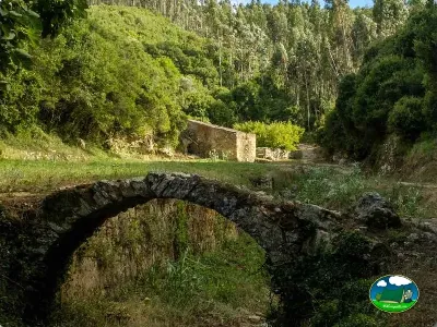 Río con puente de piedra rodeado de montaña del Camping Praia da Areia Branca, Lourinha (Lisboa)