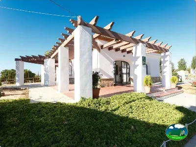 Bungalow blanco moderno con pérgola de madera del Camping La Sierrecilla, Humilladero (Málaga)
