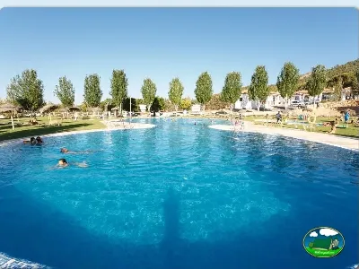 Piscina con vistas a la montaña, zona de césped y alojamientos del Camping La Sierrecilla, Humilladero (Málaga)