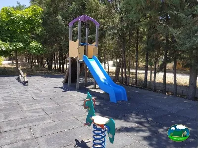 Parque infantil con tobogán y juegos entre árboles del Camping La Sierrecilla, Humilladero (Málaga)