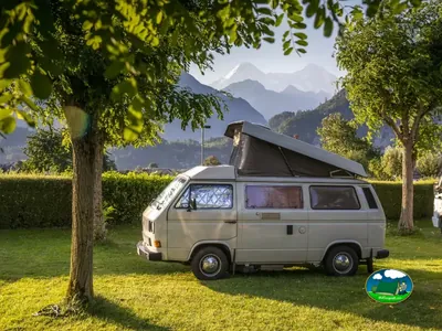 Autocaravana clásica en una parcela arbolada de Camping Lazy Rancho, Unterseen