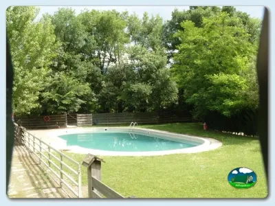 Piscina rodeada de árboles y césped del Camping Besalú, Besalú (Girona)