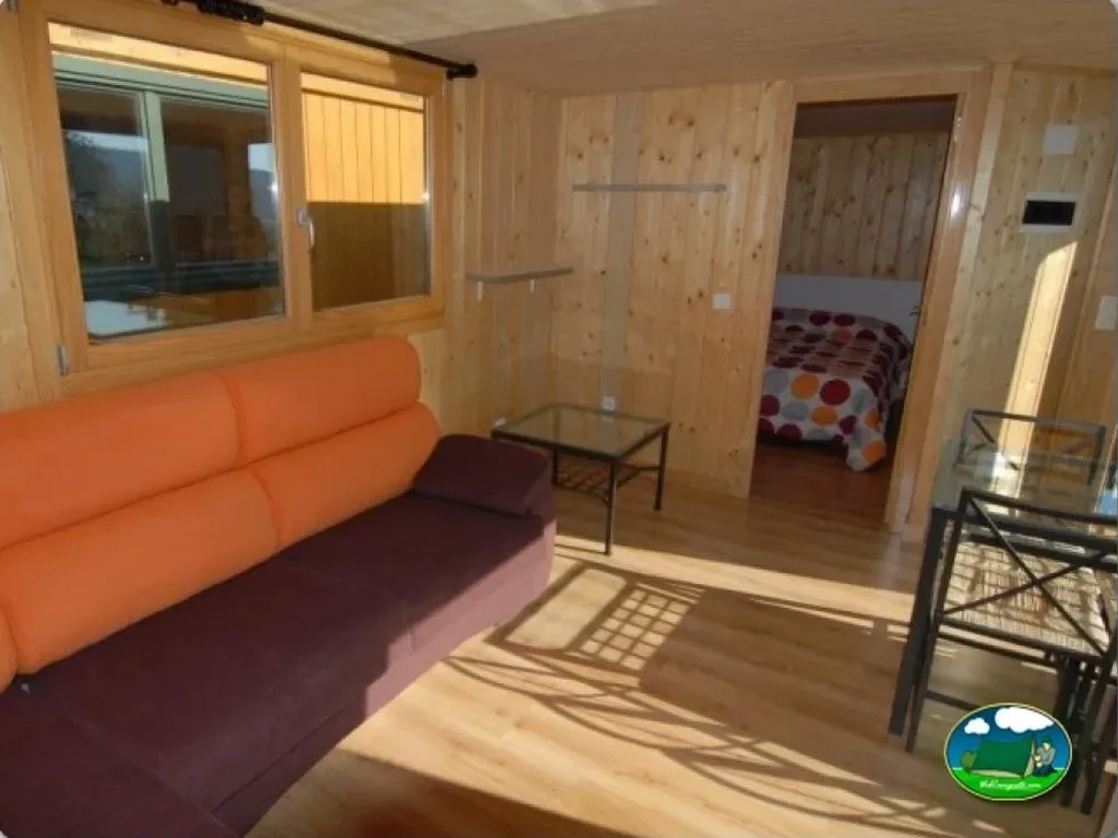 Cabaña interior con sofá y dormitorio del Camping el Roble Verde, Nuvilla (Alava)