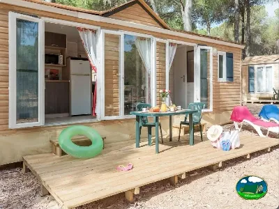 Mobil-home con terraza de madera y mesa exterior del Camping Village Doñarrayan Park, Hinojos (Huelva)