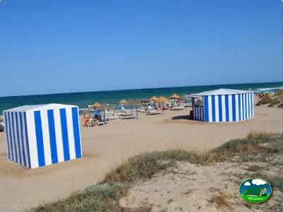 Playa junto al mar con casetas de playa azules y blancas del Camping Valencia El Saler, El Saler (Valencia)