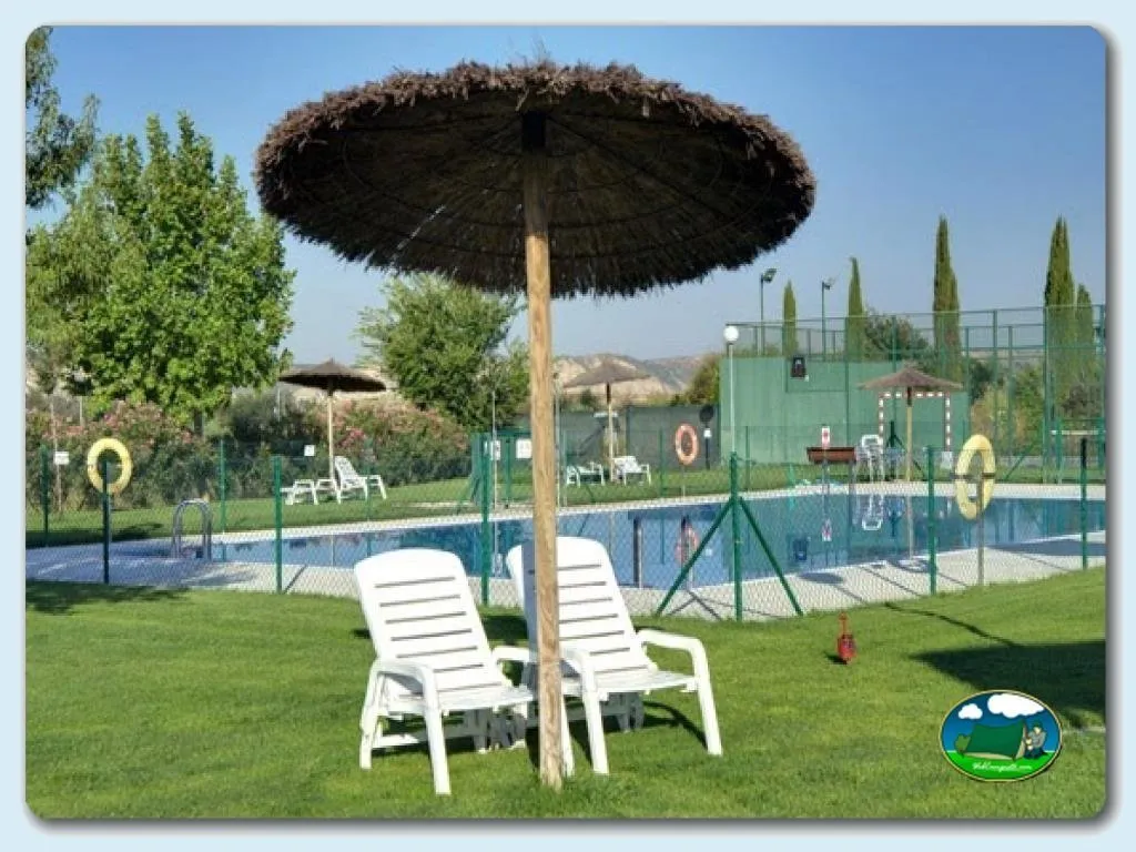 Piscina con zona de descanso y sombrilla del Camping Bardenas, Villafranca (Navarra)