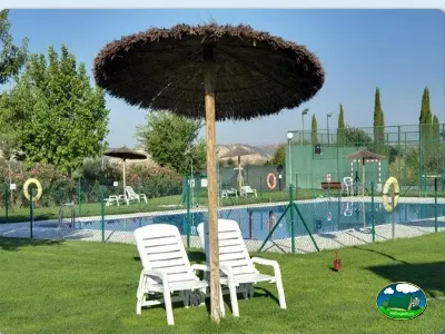 Piscina con zona de descanso y sombrilla del Camping Bardenas, Villafranca (Navarra)
