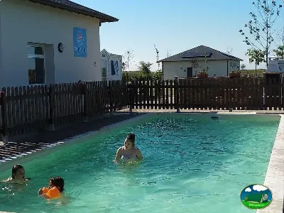 Piscina con familias bañándose y bungalows al fondo del Camping Rinlo, Rinlo (Lugo)