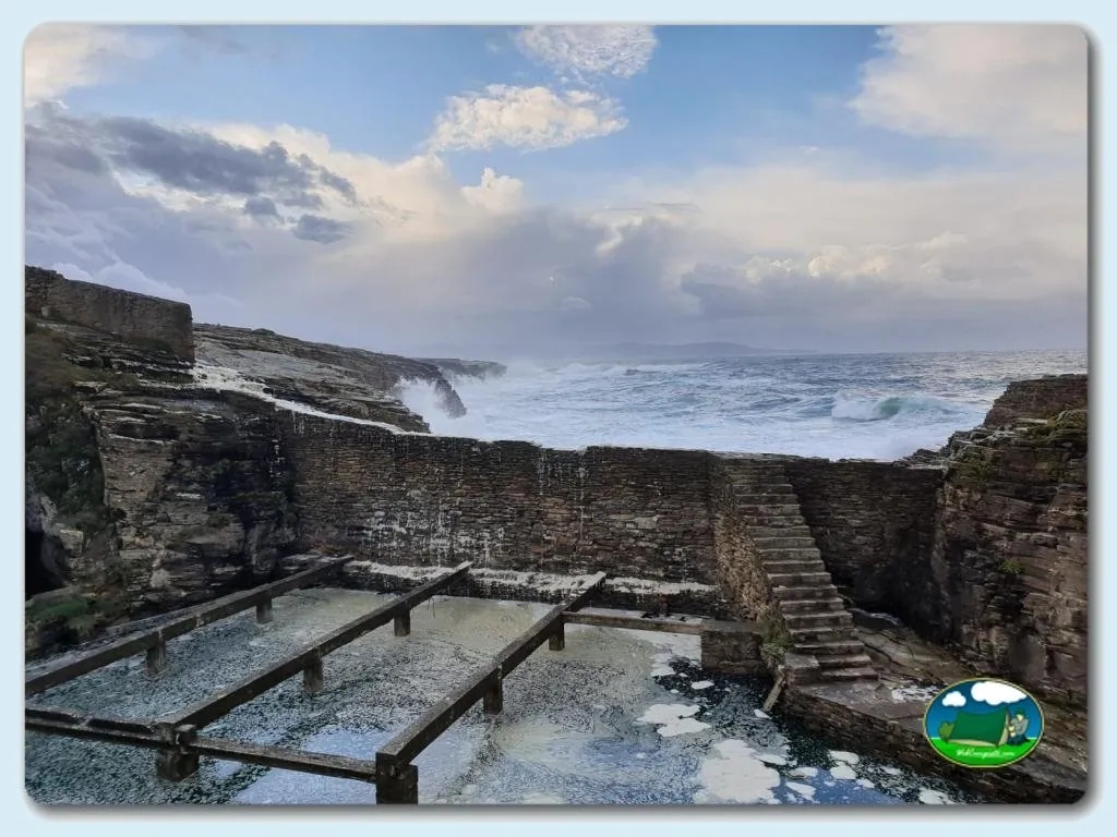 Playa junto al mar con acantilados rocosos y escaleras de acceso del Camping Rinlo, Rinlo (Lugo)