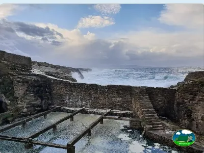 Playa junto al mar con acantilados rocosos y escaleras de acceso del Camping Rinlo, Rinlo (Lugo)