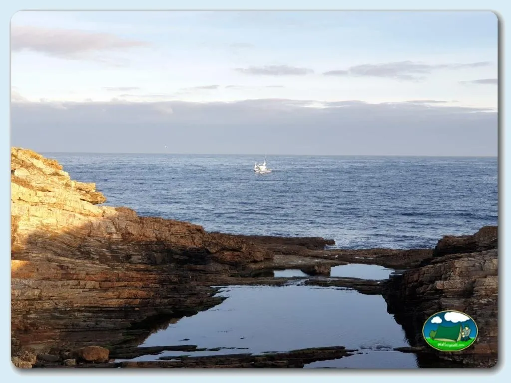 Playa junto al mar con acantilado rocoso del Camping Rinlo, Rinlo (Lugo)
