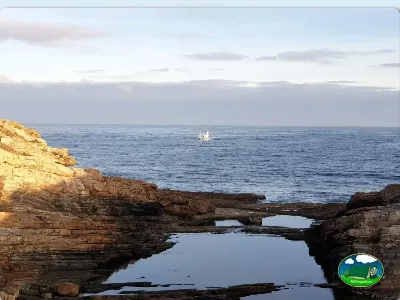 Playa junto al mar con acantilado rocoso del Camping Rinlo, Rinlo (Lugo)