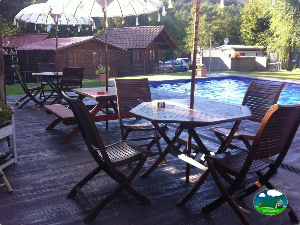 Piscina con zona de descanso y sombrilla del Camping Puigcercós, Borredà (Barcelona)