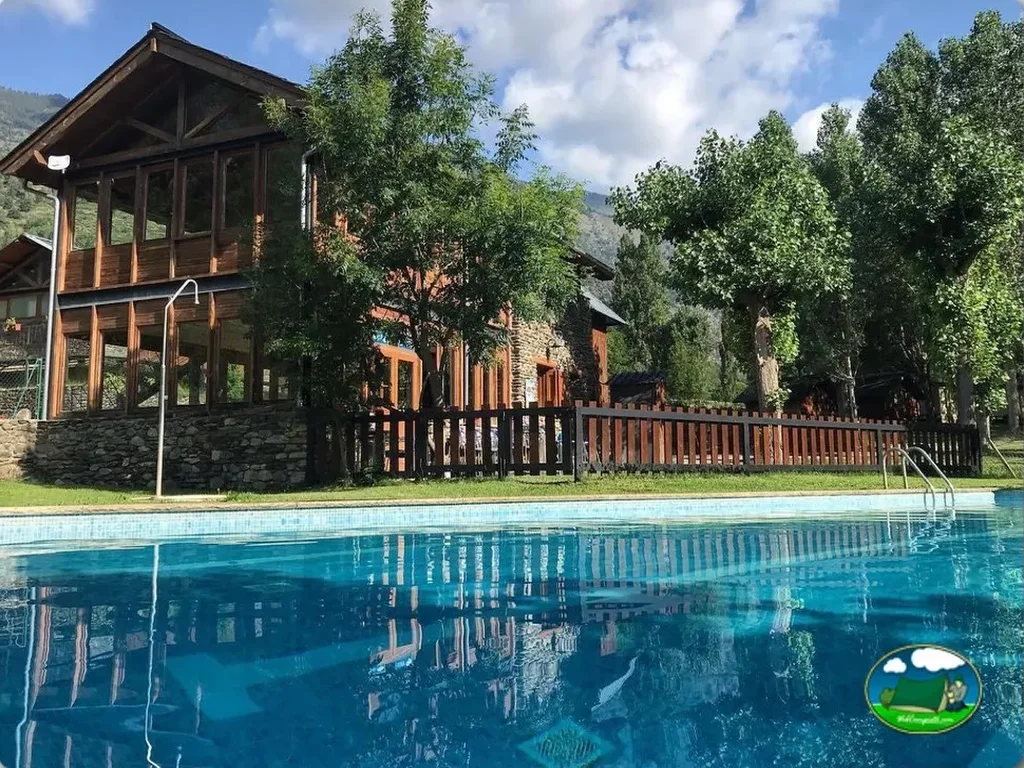 Piscina con vistas a bungalow de madera y montaña del Camping Pica d'Estats, Areu (Lleida)