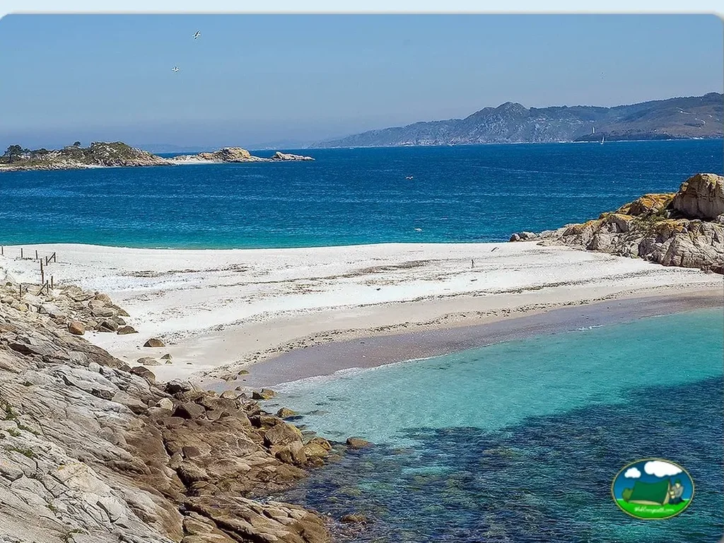 Playa junto al mar con aguas turquesas y vistas a la montaña del Camping Islas Cíes, Vigo (Pontevedra)