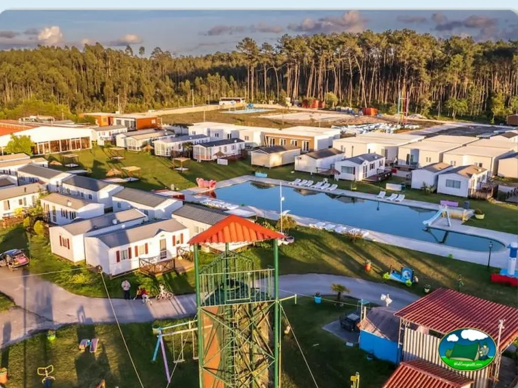 Piscina con mobil-homes y parque infantil rodeados de pinos del Camping Lands Hause Bungalows, Pataias (Leiria)