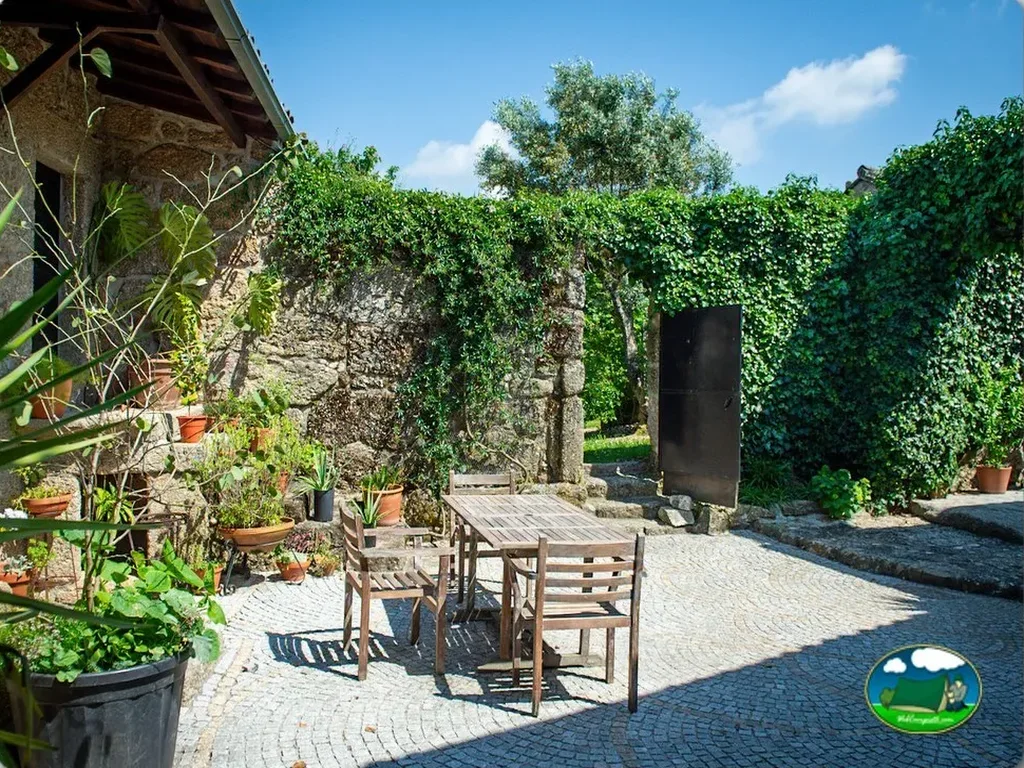 Cabaña de piedra con puerta y zona de estar del Camping Toca da Raposa, Meruge (Coimbra)