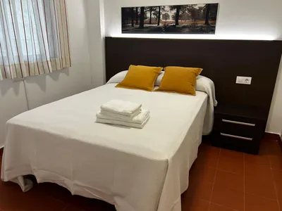 Bungalow interior con cama doble y almohadas amarillas del Camping Sierra de Gata, Gata (Cáceres)
