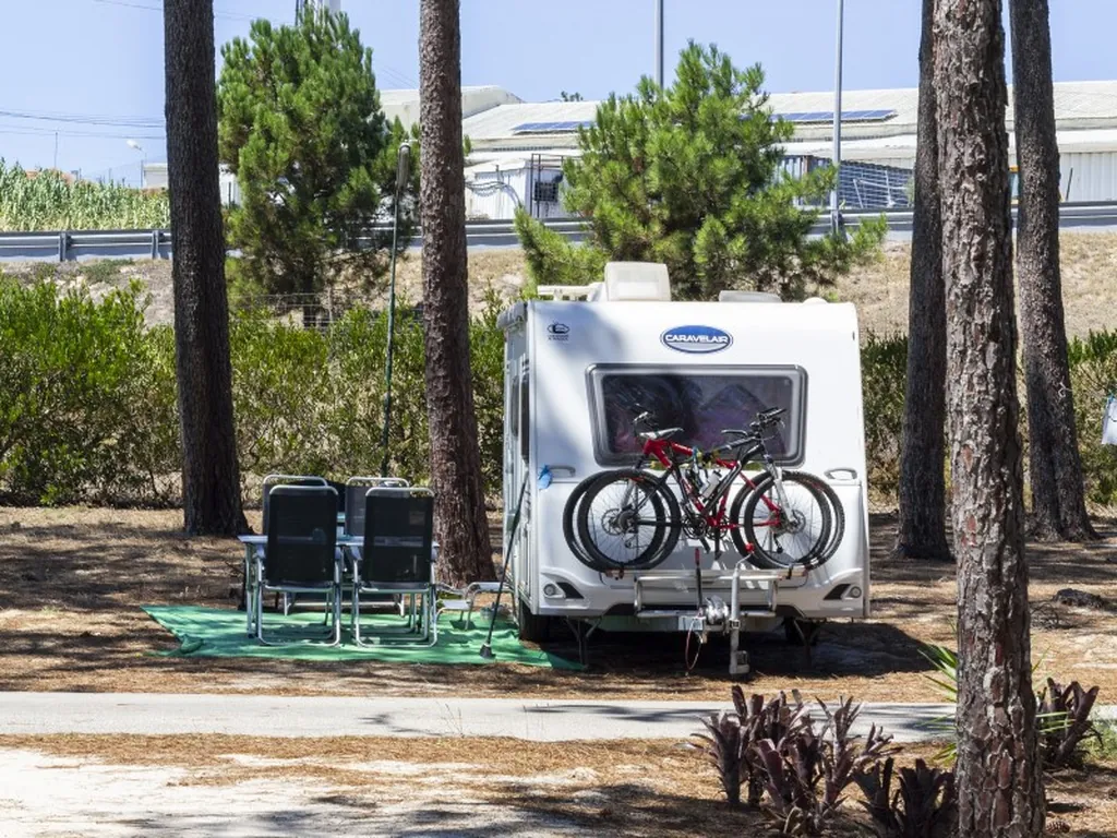 Mobil-home con bicicletas y tumbonas entre pinos del Camping Orbitur Valado, Nazaré (Leiria)