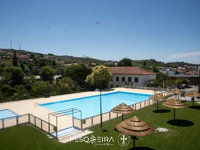Piscina con vistas a la sierra y sombrillas de paja del Camping Mata do Cabo, São João da Pesqueira (Viseu)