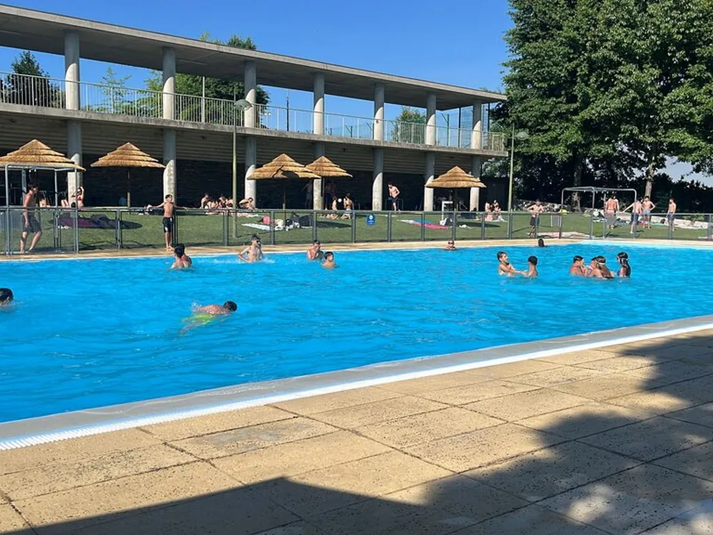 Piscina con vistas a la montaña, llena de bañistas del Camping Mata do Cabo, São João da Pesqueira (Viseu)