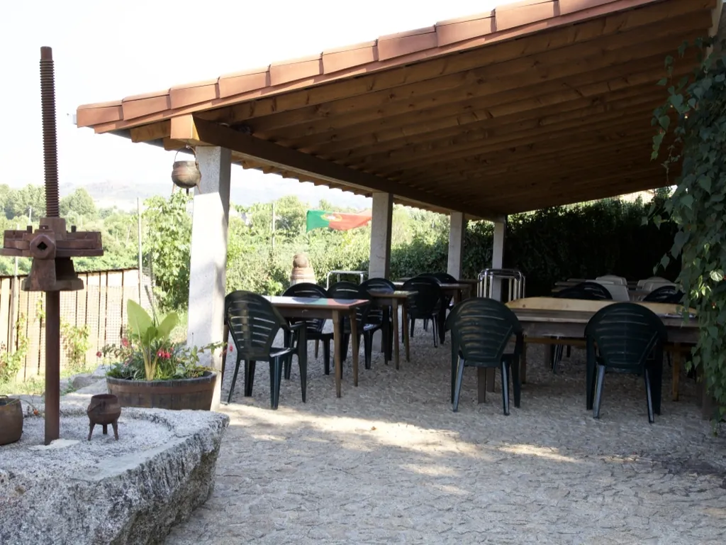 Área de descanso con mesas y sillas bajo pérgola del Camping Arco, Cabeceiras de Basto (Braga)