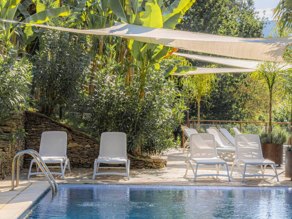 Piscina con tumbonas y velas de sombra en entorno de vegetación del Camping Quinta dos Moinhos, Cabeceiras de Basto (Braga)