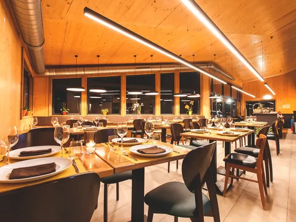 Restaurante moderno con mesas de madera y vistas nocturnas del Camping Bukubaki Eco Surf Resort, Peniche (Leiria)