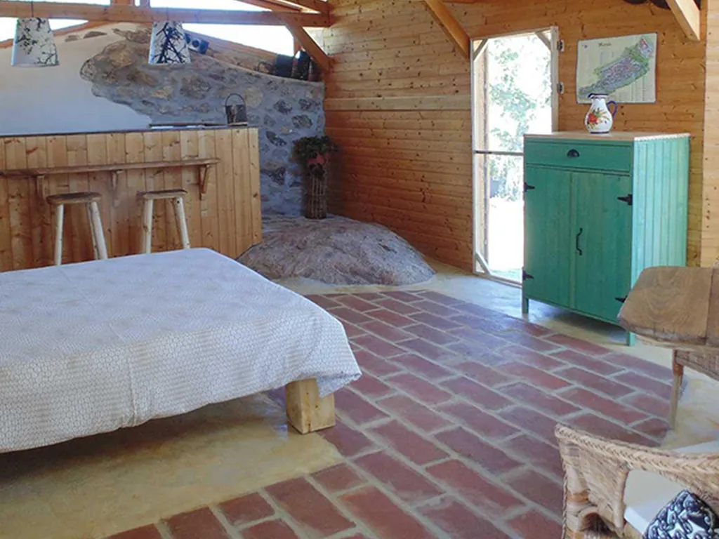 Cabaña interior con cama, cocina y mobiliario rústico del Camping Quinta do Maral - Espaço de Férias Naturista, Marvão (Portalegre)