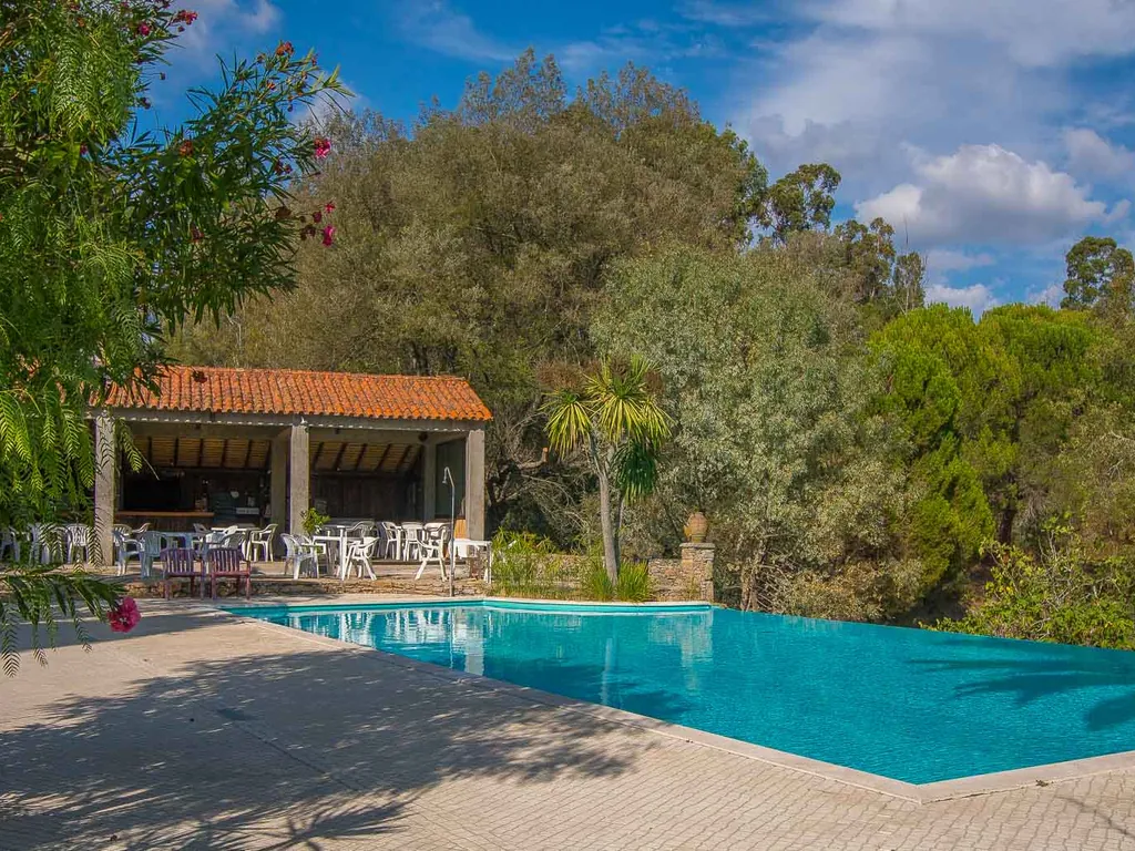 Piscina con caseta y vistas al entorno arbolado del Camping Quinta da Cerca, Tábua (Coimbra)