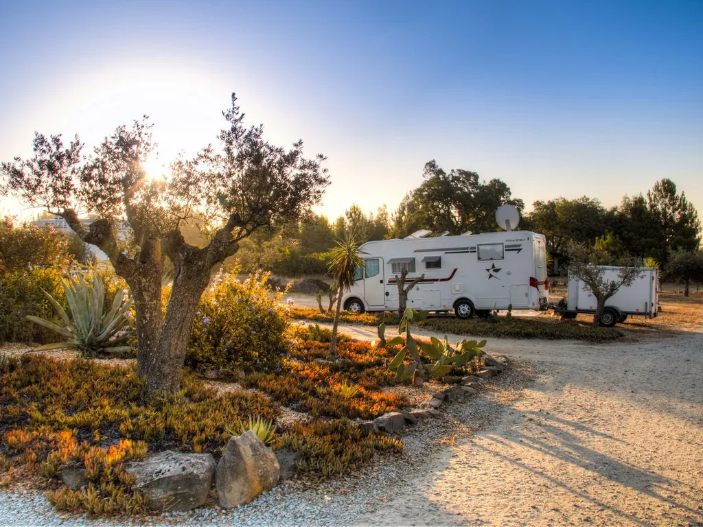 Mobil-home en parcela arbolada al atardecer del Camping Monte Naturista O Barão, Ferreira do Alentejo (Beja)