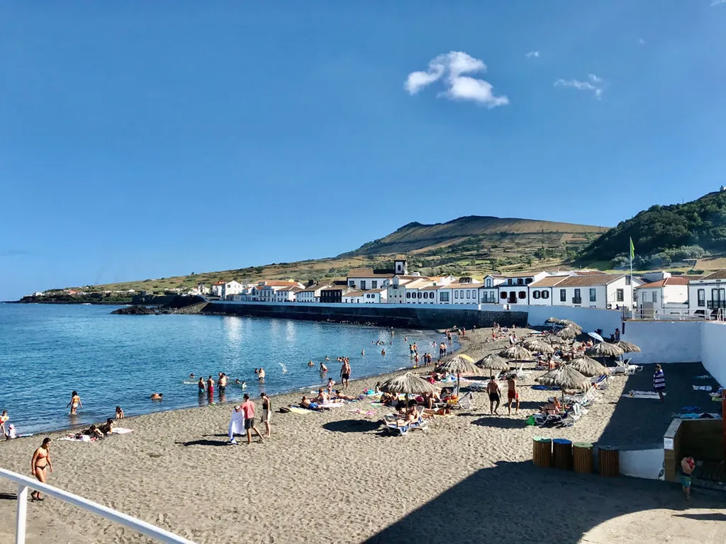 Playa junto al mar con casas blancas y montaña del Camping Parque de Campismo do Pinheiro, Santa Cruz da Graciosa (Açores)