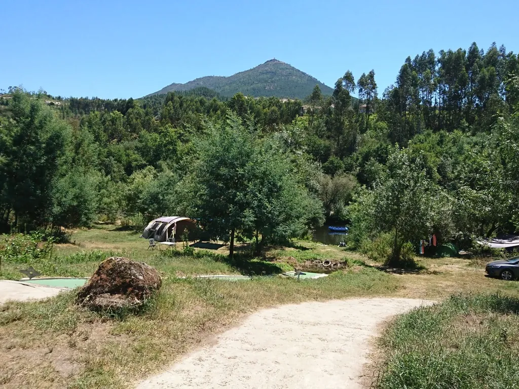Parcela con cabaña bajo montaña boscosa del Camping Quinta do Rio, Canedo de Basto (Braga)