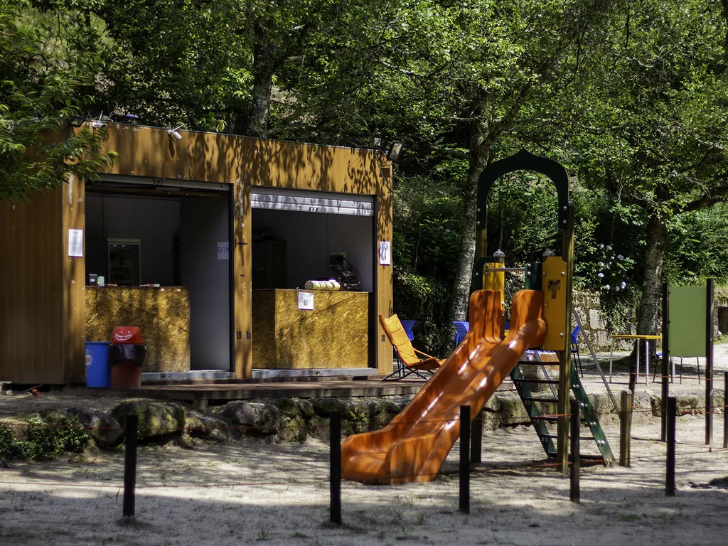 Parque infantil con tobogán y módulo de servicios del Camping Parque de Campismo do Vidoeiro (Gerês Vidoeiro Camping), Terras de Bouro (Braga)