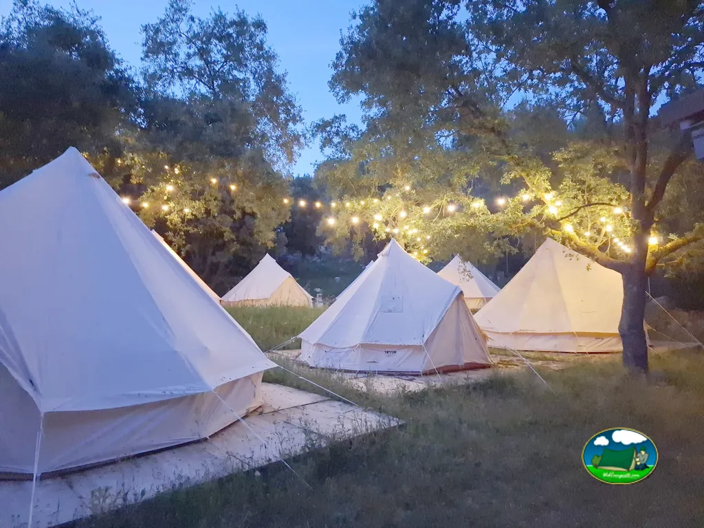 Glamping tiendas de campaña iluminadas al atardecer entre árboles del Camping Glamping La Bellota, Encinas de Esgueva (Valladolid)