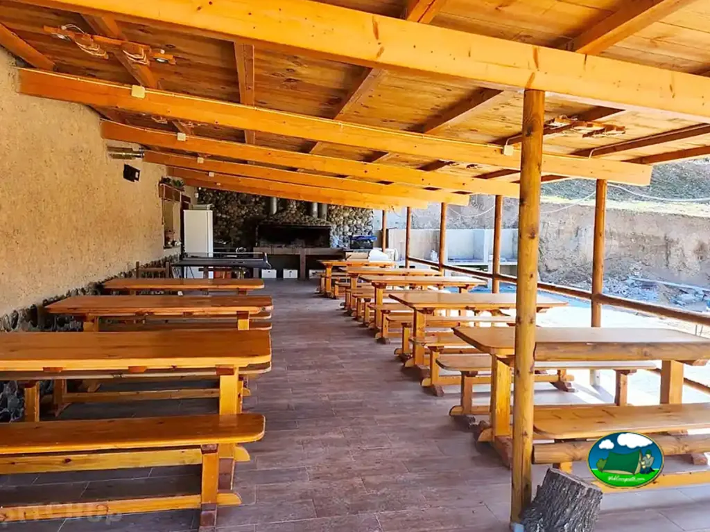 Restaurante bar con mesas de madera y vistas a montaña del Camping d'Alòs, Alòs de Balaguer (Lleida)