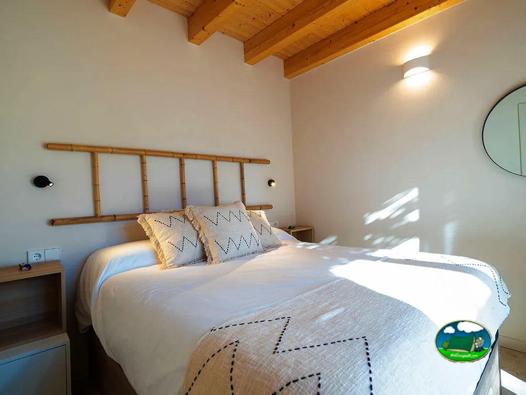 Glamping interior con cama y vigas de madera del Camping 1Respiro, Serra (Valencia)