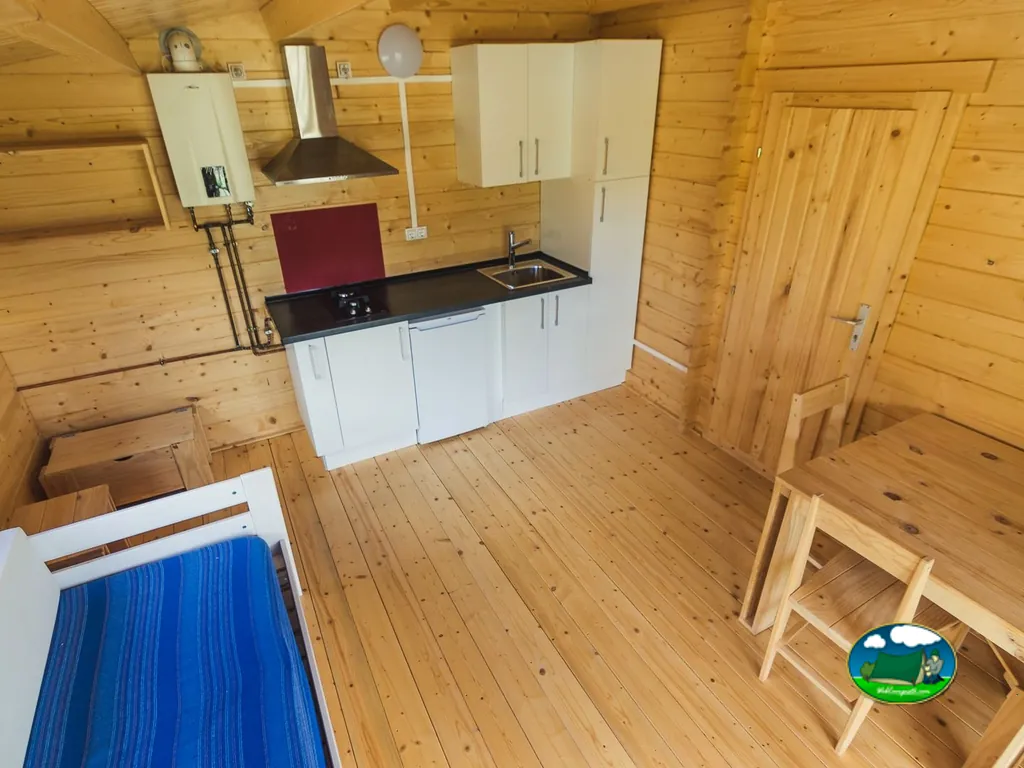 Interior cabaña con cocina equipada y cama del Camping Municipal de Artieda, Artieda (Zaragoza)
