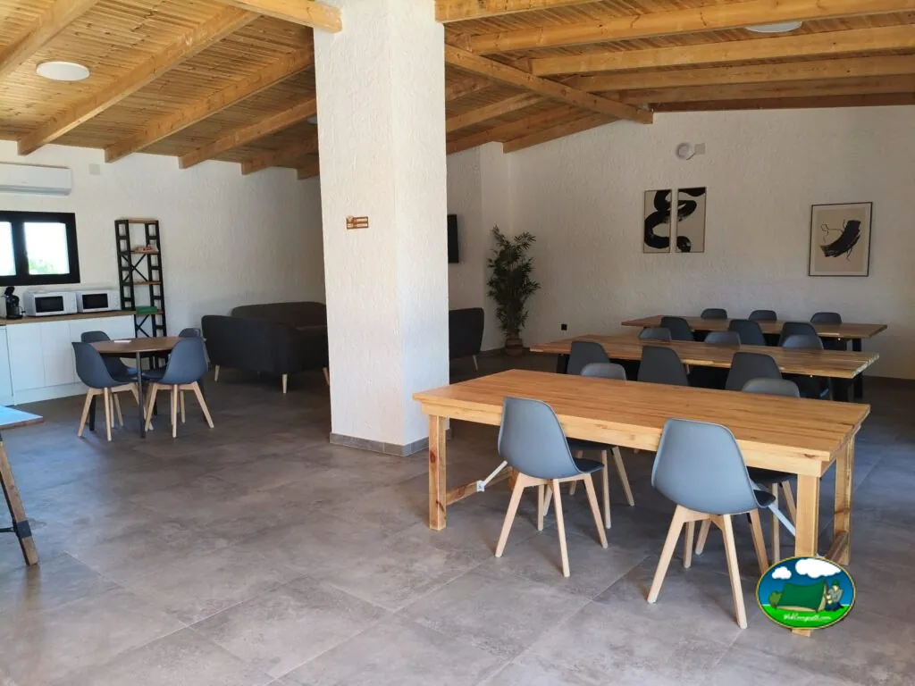 Restaurante y zona de estar con mesas de madera del Camping Alma del Cabriel, El Herrumblar (Cuenca)