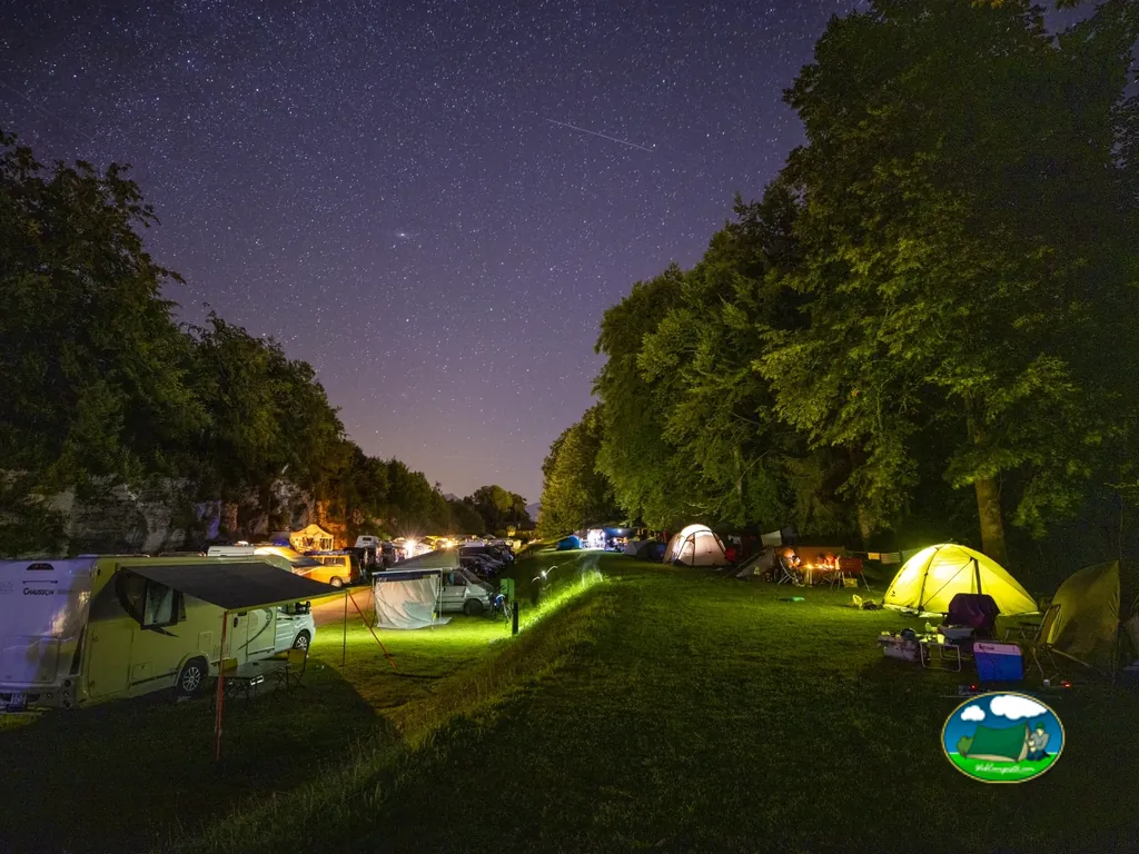Parcela nocturna con tiendas de acampada y caravanas iluminadas del Camping Talacker, Ringgenberg